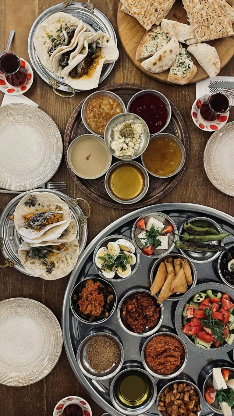 An appetizing Middle Eastern meal spread with flatbreads, dips, and teas on a rustic wooden table.